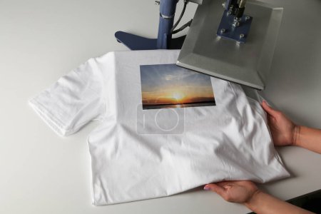 Photo for Custom t-shirt. Woman using heat press to print image of beautiful landscape - Royalty Free Image