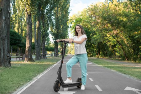 Photo for Happy woman with modern electric kick scooter in park - Royalty Free Image
