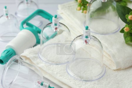 Photo for Cupping therapy. Plastic cups, hand pump and folded towels on table, closeup - Royalty Free Image
