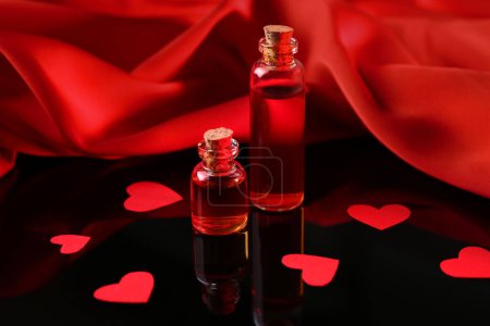 Téléchargez les photos : Bouteilles de potion d'amour, coeurs en papier et tissu rouge sur la surface du miroir - en image libre de droit