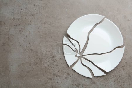 Photo for Pieces of broken ceramic plate on grey table, flat lay. Space for text - Royalty Free Image