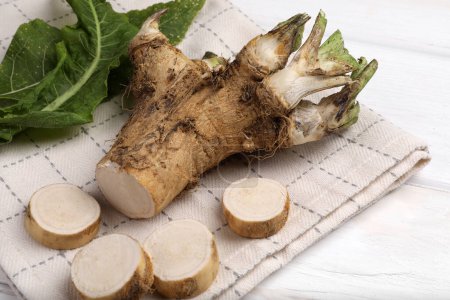 Photo for Cut horseradish root and leaves on white wooden table, closeup - Royalty Free Image
