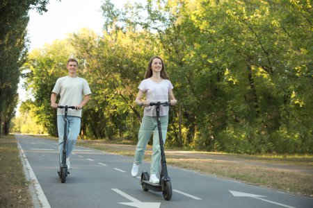 Photo for Happy couple riding modern electric kick scooters in park - Royalty Free Image