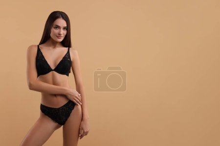 Photo for Young woman in elegant black underwear on beige background. Space for text - Royalty Free Image