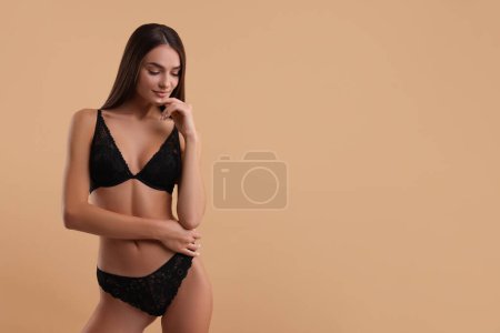 Photo for Young woman in elegant black underwear on beige background. Space for text - Royalty Free Image