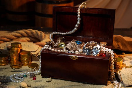 Coffre avec trésors et sable éparpillé sur table en bois