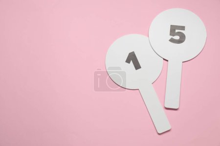 Photo for Auction paddles with numbers on pink background, top view. Space for text - Royalty Free Image