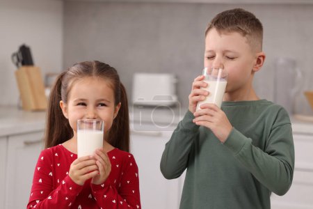 Téléchargez les photos : Enfants mignons boire du lait frais à partir de verres dans la cuisine - en image libre de droit