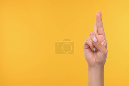 Foto de Mujer cruzando los dedos sobre fondo amarillo, primer plano. Espacio para texto - Imagen libre de derechos