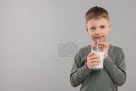 Téléchargez les photos : Mignon garçon avec verre de lait frais sur fond gris clair, espace pour le texte - en image libre de droit