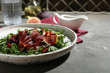 Photo for Plate of tasty bresaola salad with figs, sun-dried tomatoes and balsamic vinegar on grey table, closeup. Space for text - Royalty Free Image