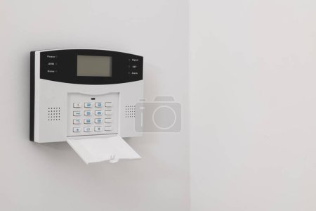 Foto de Sistema de alarma de seguridad doméstica en pared blanca en interiores, espacio para texto - Imagen libre de derechos