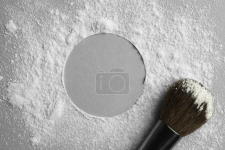 Frame made of rice loose face powder and makeup brush on light grey background, top view. Space for text