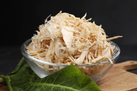 Photo for Grated horseradish in bowl, leaf and board on black table, closeup - Royalty Free Image