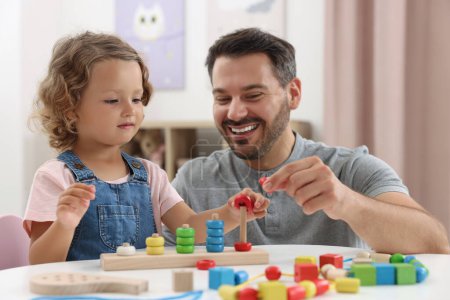 Développement des compétences motrices. Père et fille jouant avec empilement et jeu de comptage à la table à l'intérieur