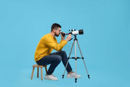 Astronomer looking at stars through telescope on light blue background