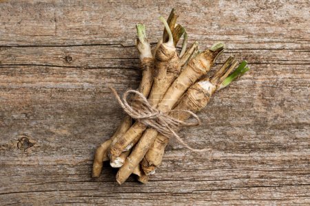Photo for Bunch of fresh horseradish roots on wooden table, top view - Royalty Free Image