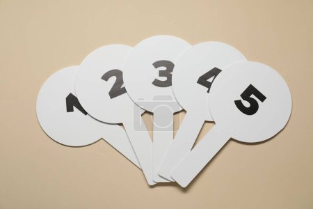 Photo for Auction paddles with numbers on beige background, flat lay - Royalty Free Image