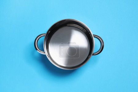 Photo for Empty steel pot on light blue background, top view - Royalty Free Image
