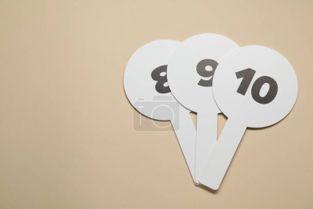 Photo for Auction paddles with numbers on beige background, flat lay. Space for text - Royalty Free Image