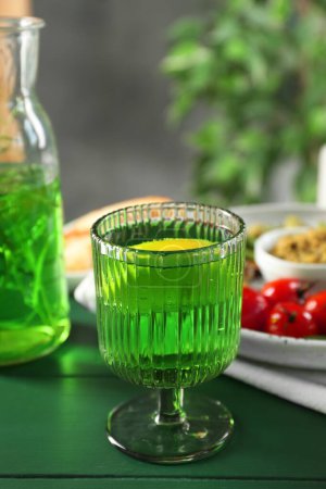 Delicious drink with tarragon in glass on green table. Space for text