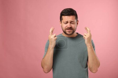 Foto de Hombre emocional cruzando los dedos sobre fondo rosa, espacio para el texto - Imagen libre de derechos