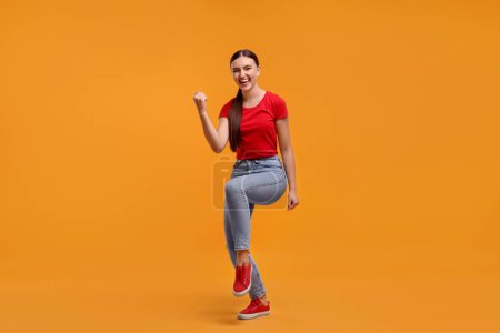 Glücklicher Sportfan feiert auf orangefarbenem Hintergrund
