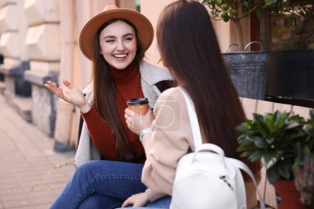 Téléchargez les photos : Amis heureux avec des tasses en papier de café parler à l'extérieur - en image libre de droit