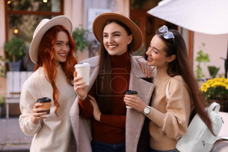 Téléchargez les photos : Heureux amis avec des tasses en papier de café passer du temps ensemble dans la rue de la ville - en image libre de droit