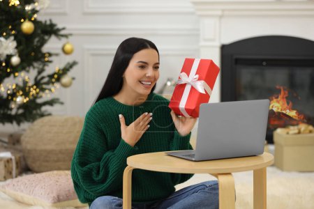 Célébrons Noël en ligne avec des cadeaux échangés par la poste. Femme souriante remerciant pour le cadeau lors d'un appel vidéo à la maison