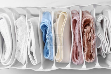 Photo for Organizer with folded women's underwear on white marble table, top view - Royalty Free Image