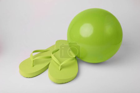 Téléchargez les photos : Balle de plage gonflable verte et tongs sur fond blanc - en image libre de droit
