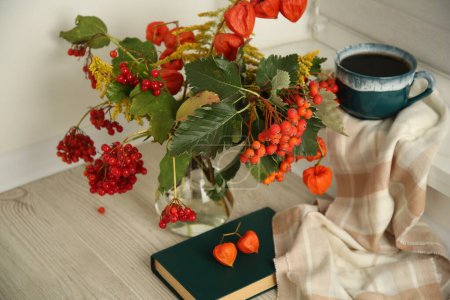Beautiful autumn composition with cup of drink and book indoors