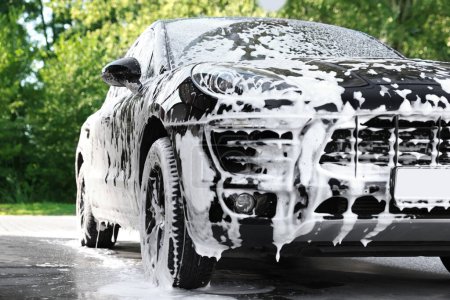 Foto de Auto cubierto con espuma de limpieza en el lavado de coches al aire libre - Imagen libre de derechos