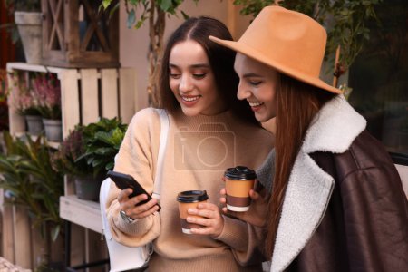 Téléchargez les photos : Ami heureux avec smartphone et tasses en papier à l'extérieur - en image libre de droit