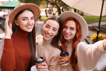 Téléchargez les photos : Heureux amis avec des tasses en papier de prise de café selfie dans le parc - en image libre de droit