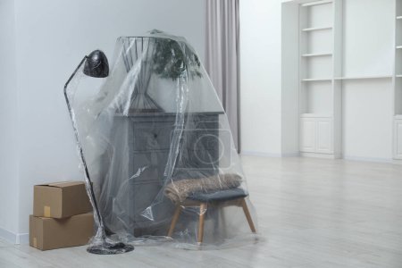 Foto de Muebles modernos, planta de interior cubierta con película de plástico y cajas en casa. Espacio para texto - Imagen libre de derechos