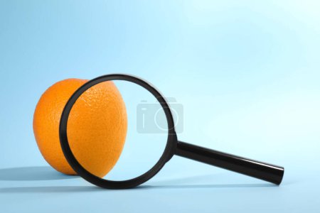 Téléchargez les photos : Problème de cellulite. Pelure d'orange zoomée sur fond bleu clair, vue à travers loupe. Espace pour le texte - en image libre de droit