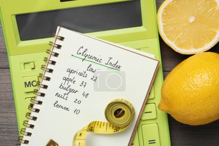 Notebook with products of low glycemic index, calculator, measuring tape and lemons on wooden table, top view