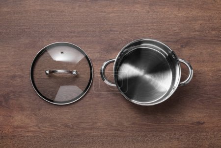 Photo for Steel pot and glass lid on wooden table, flat lay - Royalty Free Image