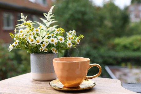 Photo for Cup of delicious chamomile tea and fresh flowers outdoors. Space for text - Royalty Free Image