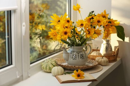 Komposition mit schönen Blumen, Kürbissen und Buch auf Fensterbank. Herbststimmung
