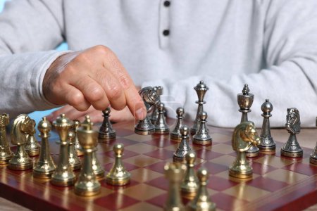 Man with knight playing chess at checkerboard, closeup