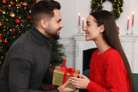Foto de Hombre feliz dando regalo de Navidad a su novia en casa - Imagen libre de derechos