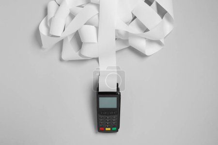 Foto de Terminal de pago con papel térmico para recibo sobre fondo gris claro, vista superior - Imagen libre de derechos