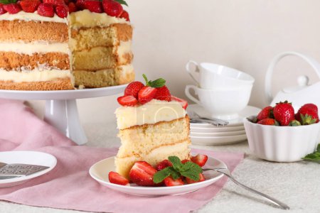 Piece of tasty cake with fresh strawberries and mint on white table