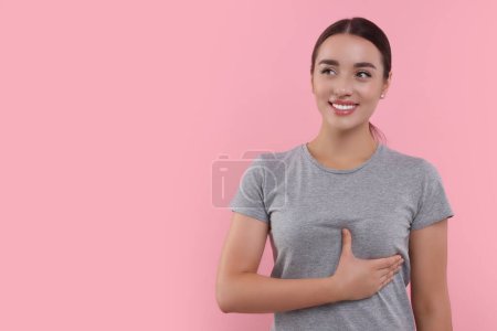 Belle femme heureuse faisant l'auto-examen des seins sur fond rose. Espace pour le texte