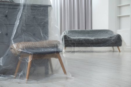 Téléchargez les photos : Commode, tabouret et canapé gris recouverts de film plastique à la maison - en image libre de droit