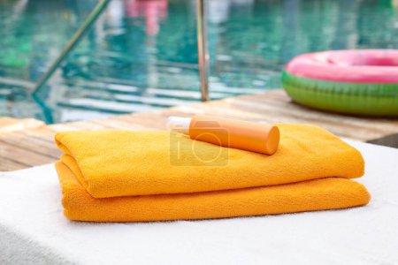 Photo for Beach towels and sunscreen on sun lounger near outdoor swimming pool, selective focus. Luxury resort - Royalty Free Image