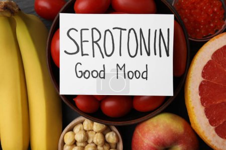 Muchos productos diferentes y tarjeta con la frase Serotonin Good Mood en la mesa, la puesta plana. Antidepresivos naturales